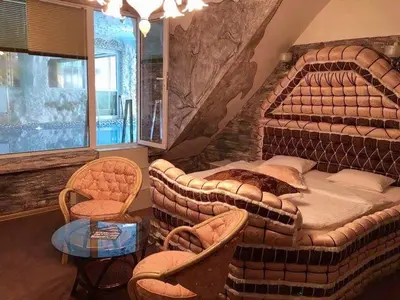 a bedroom with a large bed and chairs and a table at Bali Colosseum Hotel in Belgrade
