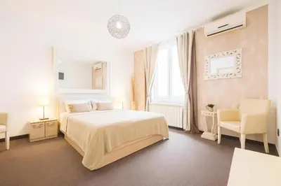 a white bedroom with a bed and two chairs at Central Belgrade Apartments in Belgrade