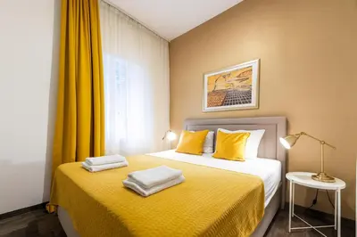 a bedroom with a bed with yellow sheets and a window at Central Belgrade Apartments in Belgrade