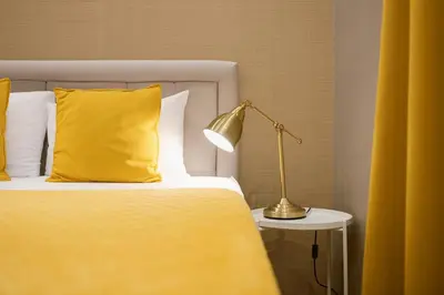 a bed with a yellow blanket and a lamp on a table at Central Belgrade Apartments in Belgrade