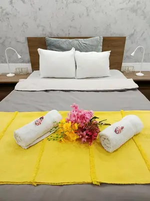 a bed with two towels and flowers on it at Urban Garden Apartments - Iris in Belgrade