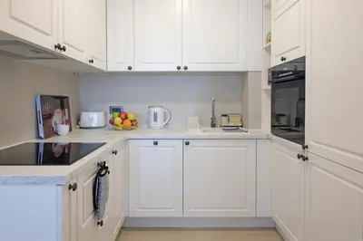 a white kitchen with white cabinets and a bowl of fruit at New Luxury Dorcol Downtown Apartment in Belgrade