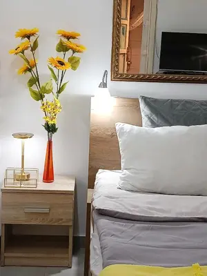 a vase of flowers on a night stand next to a bed at Urban Garden Apartments - Sunflower in Belgrade