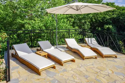 four lounge chairs and an umbrella on a patio at Vila Gospođica in Progar