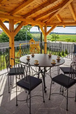 a table and chairs on a patio with a wooden roof at Vila Gospođica in Progar