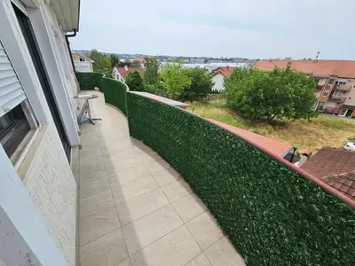 a balcony with a green hedge and a walkway at Zora apartment in Belgrade