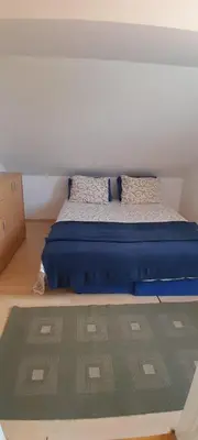 a bedroom with a bed with a blue mattress and a rug at Airport Nikki Apartments in Belgrade