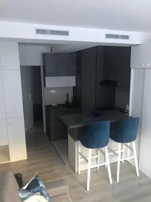 a kitchen with a counter and two blue chairs at Beograd stan na dan in Novi Beograd