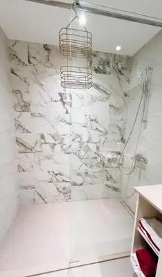 a bathroom with a shower with white marble walls at BW Maca - Arcadia in Belgrade