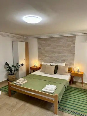 a bedroom with a large bed with a green blanket at M Place in Mirijevo