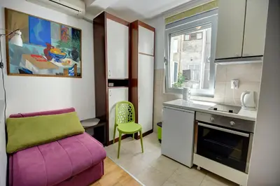 a small kitchen with a purple couch and a table at Sekula's City Center Apartment in Belgrade