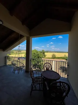 a balcony with tables and chairs and a view of a field at Casa Lisović in Lisović