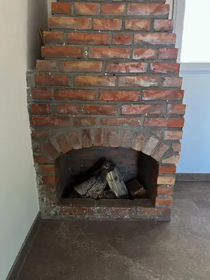 a brick fireplace with a pile of wood in it at Casa Lisović in Lisović