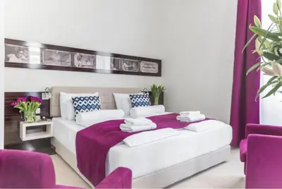 a bedroom with a large white bed with purple accents at Theater Hotel Belgrade in Belgrade