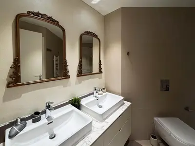 a bathroom with two sinks and a toilet and mirrors at BW City Elegance Collection in Belgrade