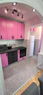 a kitchen with pink cabinets and a white refrigerator at Lux Apartman Stojanović in Belgrade