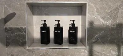 three black electric toothbrushes in a holder on a wall at Lux Apartman Stojanović in Belgrade
