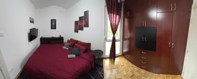 a bedroom with a red bed and a tv at Lux Apartman Stojanović in Belgrade