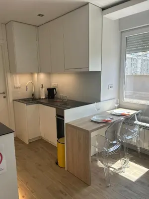a kitchen with white cabinets and a table and chairs at Chic City Studio in Belgrade