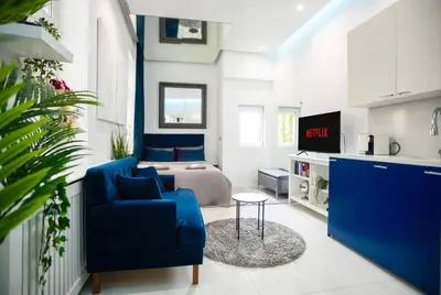 a living room with a blue chair and a bed at City center - Mirror apartment in Belgrade