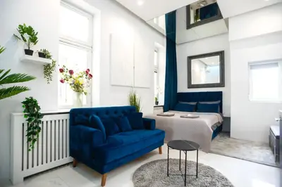 a living room with a blue couch and a bed at City center - Mirror apartment in Belgrade