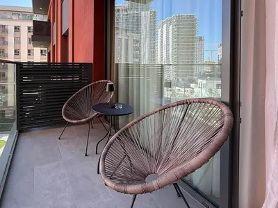 a balcony with two chairs and a table and a window at BW Crown Garden Residences in Belgrade