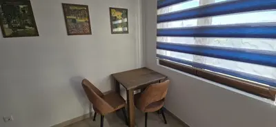 a small table and two chairs in a room with a window at Apartman Gora in Irig
