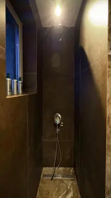 a bathroom with a shower with a light on the wall at Ollio Balkan Escape in Belgrade