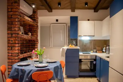 a kitchen with a table with orange chairs and blue cabinets at Ollio Balkan Escape in Belgrade
