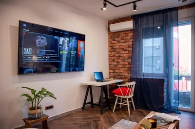 a living room with a table and a tv on the wall at Ollio Balkan Escape in Belgrade