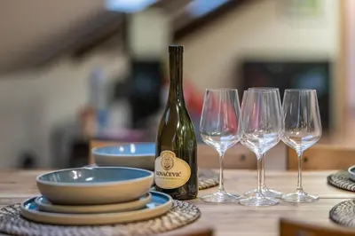 a table with a bottle of wine and three wine glasses at The Belfort Townhomes - Green Lux Loft in Belgrade