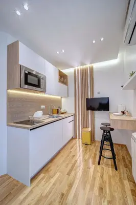 a kitchen with white cabinets and a bar stool at Spa King Apartments 3 in Belgrade