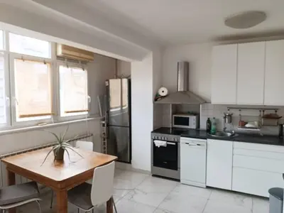 a kitchen with white cabinets and a wooden table at Relax Apartment in Belgrade
