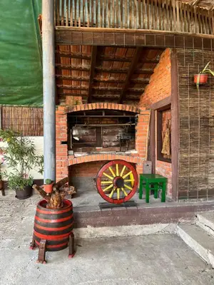 a brick oven with a wheel and a green bench at Loza House in Arandjelovac