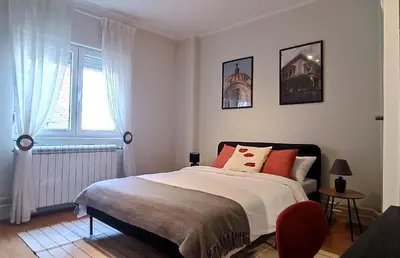 a bedroom with a bed with red pillows and a window at Resava Apartment in Belgrade