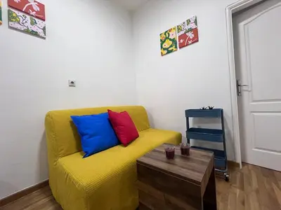 a yellow couch with colorful pillows in a living room at The Cozy George Apartment in Belgrade