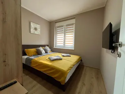a bedroom with a bed with yellow sheets and a window at Apartman Momirov Titel