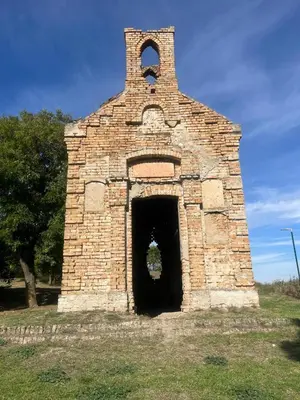 an old brick building with a doorway in a field at Apartman Momirov Titel