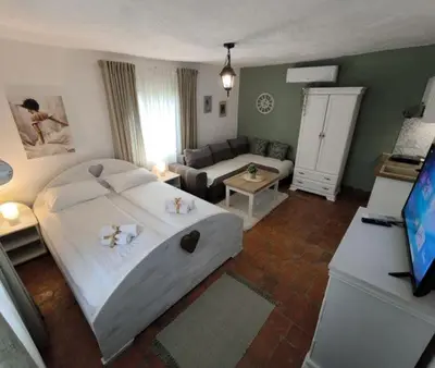 a bedroom with a large bed and a living room at Apartmani Etno Selo Americ