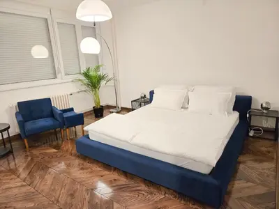a bedroom with a large bed and a blue chair at High White apartments 2 NEW in Belgrade