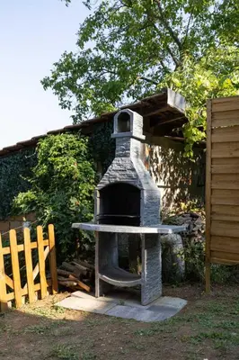 a stone oven sitting next to a wooden fence at Kućica na brdu-Zaklopača in Zaklopača