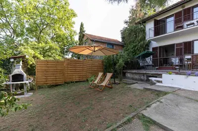 a patio with an umbrella and chairs in a yard at Kućica na brdu-Zaklopača in Zaklopača