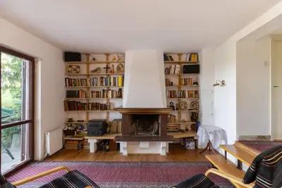 a living room with a fireplace and shelves of books at Kućica na brdu-Zaklopača in Zaklopača
