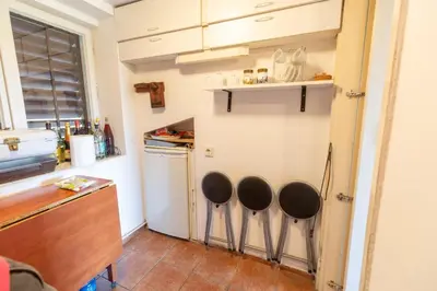 a kitchen with three stools in front of a refrigerator at Kućica na brdu-Zaklopača in Zaklopača