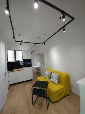 a living room with a yellow couch and a kitchen at Don apartment Dorcol in Belgrade