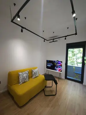 a living room with a yellow couch and a flat screen tv at Don apartment Dorcol in Belgrade