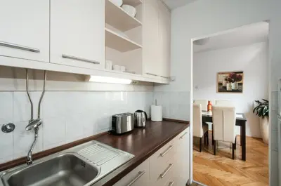 a kitchen with white cabinets and a sink and a table at Sensitive Apartment in Belgrade