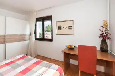 a bedroom with a desk and a table with a red chair at Sensitive Apartment in Belgrade