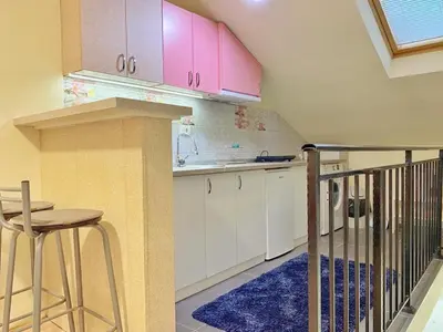 a kitchen with white cabinets and a table and stool at Stay at Balkanska 45 in Belgrade
