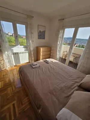 a bedroom with a large bed with large windows at Apartman Emi in Belgrade